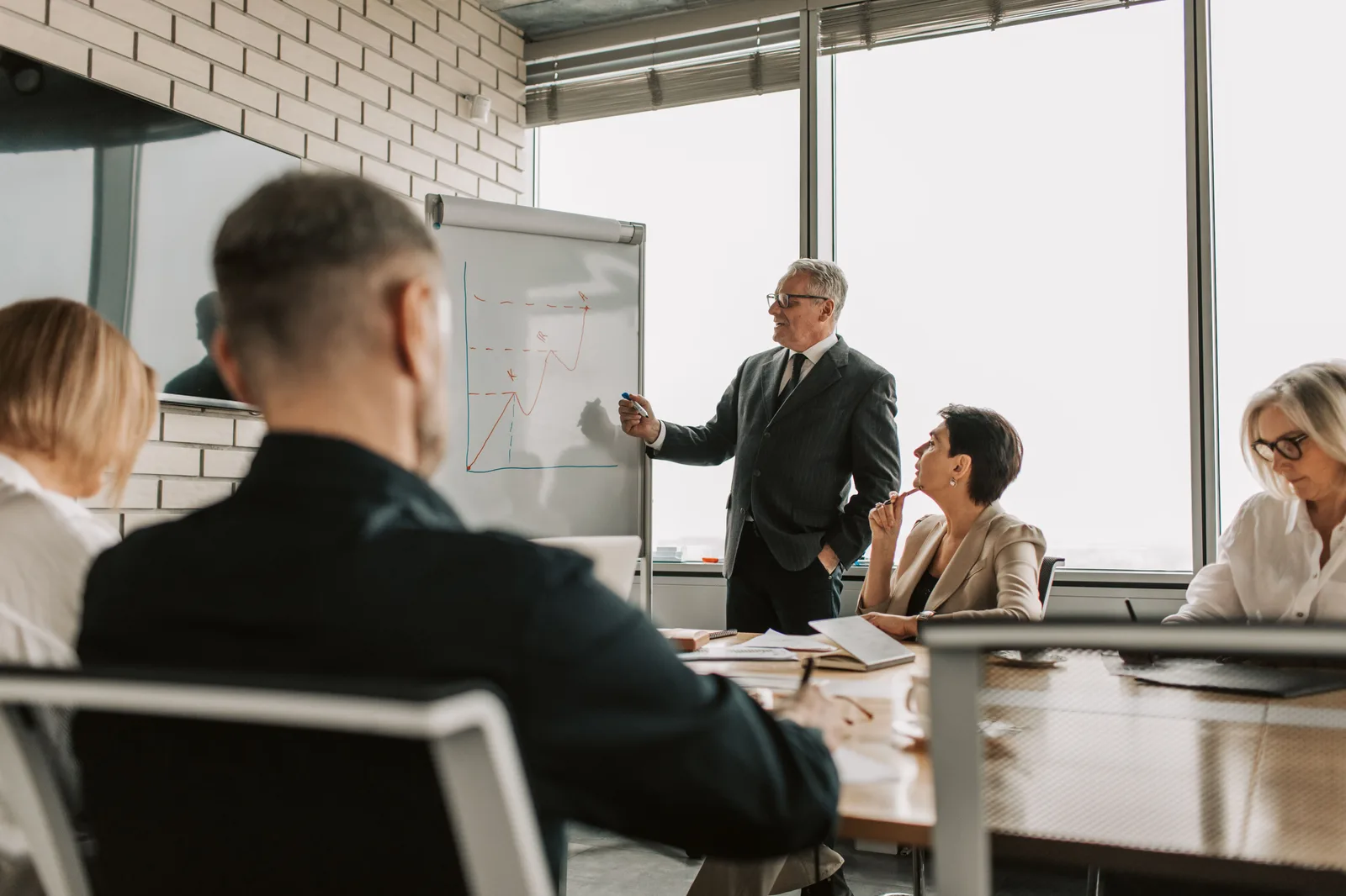 Senior leader presenting growth charts in a business meeting with colleagues in a modern office setting. Corporate responsibility framework: the parts worth your attention
