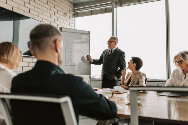 Senior leader presenting growth charts in a business meeting with colleagues in a modern office setting. Corporate responsibility framework: the parts worth your attention
