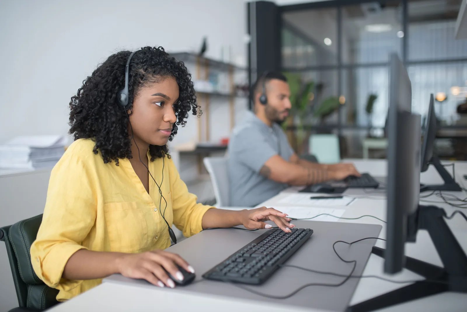 Two customer service agents working with headsets in a modern office setting. The honest guide to an invented customer ethics case study
