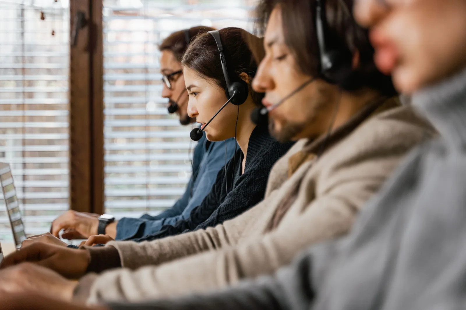 Focused customer support team using headsets and laptops in a busy office setting. Customer ethics checklist, from first line to sign-off
