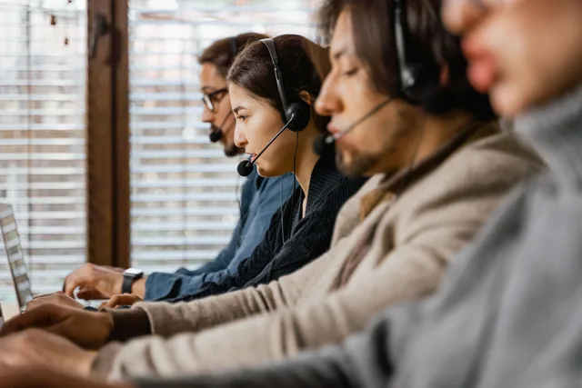 Focused customer support team using headsets and laptops in a busy office setting. Customer ethics checklist, from first line to sign-off