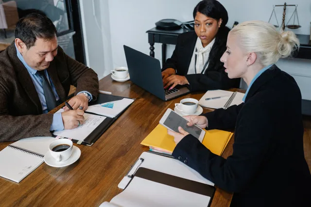 From above of multiracial colleagues in formal outfit working with papers laptop and tablet at table. How to answer the customer ethics questions leadership actually asks